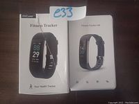 Photo of the two packed fitness tracker bracelets in their retail boxes, showing front panel images and branding.
