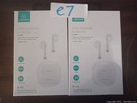 Two boxed sets of USAMS IA Series True Wireless Earbuds in white with charging cases visible on front packaging. Bluetooth 5.0 and noise cancelling features indicated on boxes.