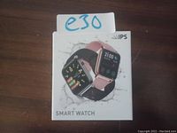Photo of the IPS Smart Watch retail box showing images of the smartwatch in black and pink silicone bands on the front with digital display.