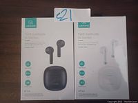 Photo of two USAMS True Wireless Earbuds boxes, one black set and one white set, both sealed in packaging.