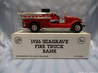 Diecast fire truck model displayed on original box, showing front and side profile of red fire truck with chrome ladders and wheels.