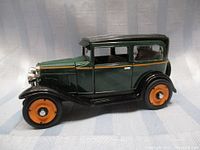 Side profile view of the 1930 Chevrolet coach model car showing green paint, black fenders, and orange wheels.