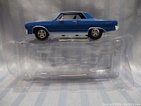 Blue 1/32 scale model of a 1965 Malibu Super Sport car with black roof, mounted on clear plastic packaging.