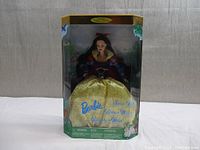Full view of Barbie Snow White doll in original box. Doll wears a blue and yellow dress with red accents. Box shows minor wear but sealed.