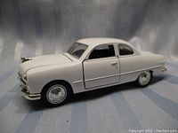 White scale model of a classic Ford car from side front view.