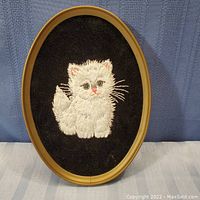 Oval framed black velvet picture with hand stitched white kitten centered, approximate size 5 x 7 inches.