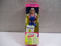 Full front view of Barbie in box showing packaging and doll with shopping bag accessory.