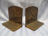 Pair of heavy antique metal bookends with embossed cowboy and cattle scene