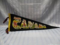 Full view of the black felt pennant with CANADA spelled out in large letters featuring multiple Canadian landmarks and scenes inside the letters.
