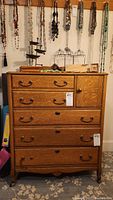Front view showing the antique oak dresser with 5 drawers and a cabinet door, including carved shell detail at the top center.