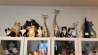 Wide view showing multiple Nina Lyman cat sculptures and other cat decor arranged on top of cabinets.