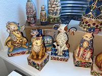 Front-row cat figurines “Curiosity,” “Vigilance,” “Freedom” and bell-holding cat on bases