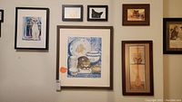 Six framed cat-themed artworks mounted on a wall arranged in two rows, showing a variety of cat images and styles