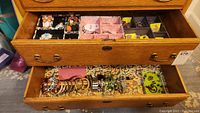 Top drawer with divided compartments holding assorted rings, brooches, and small jewelry pieces