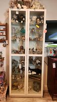 Front view of the white Ikea display cabinet filled with various collectibles and figurines visible behind glass doors.