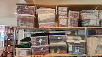 Wide shot of top two metal shelves holding plastic bins filled with folded fabric in various colors and patterns