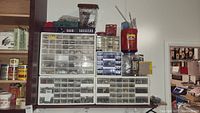 Overall view of multiple stacked storage bins containing various hardware items such as metal parts and small components.