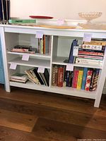 Front view of the white wood bookcase filled with various hardcover and spiral-bound books.