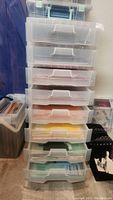 Front view of tall clear plastic organizer with 8 drawers filled with colorful scrapbooking paper.