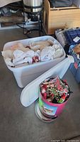 White plastic storage tote and decorative round tin with lids removed showing contents