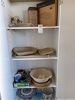 Shelves with Pampered Chef boxes, ceramic dishes, glass jars, and kitchen items