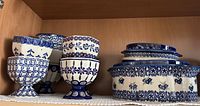 Polish pottery bowls and pitchers displayed on a shelf showing blue and white patterns