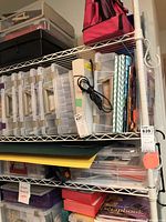 Shelves with multiple plastic totes filled with scrapbooking supplies and tools, including paper and crafting accessories.