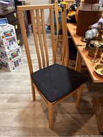 Front view of one teak dining chair showing slatted back and upholstered seat