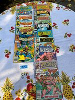 Photo of 13 vintage comic books laid out on a table with pineapple and floral print tablecloth.