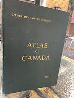 Green hardcover with gold embossed title 'Department of the Interior ATLAS OF CANADA 1915' representing the front cover of the atlas.