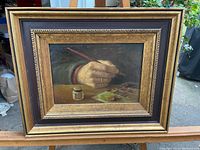 Framed oil painting showing hand, brush, palette and ink jar against outdoor background
