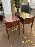 Pair of antique mahogany end tables with visible curved legs and glass tops.