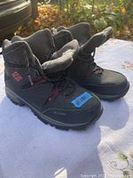 Pair of black Columbia winter boots with red logo on side and red details on laces, showing overall condition and style.