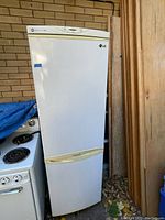 Full front view of the tall narrow white LG refrigerator showing the freezer at the bottom and fridge door above.