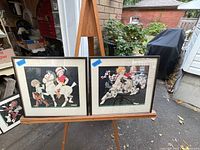 Two framed Art Deco prints displayed on an easel outdoors, showing the pair of period prints each featuring children riding horses.