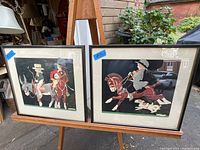 Pair of framed Art Deco period prints displayed on an easel outdoors with visible details of the subjects and style