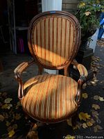 Full front view of the Victorian gentleman's armchair showing striped upholstery and wooden frame.