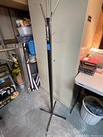 Full view of a single vintage all metal coat tree showing the tripod base and upper hooks.