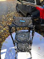 Front view of plant stand showing three tiers and decorative filigree shelves