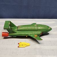Side view of green Thunderbird 2 toy with small yellow shuttle in front, showing paint wear