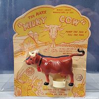 Front view of Marx Milky Cow toy mounted on original card with detailed branding and instructions visible.