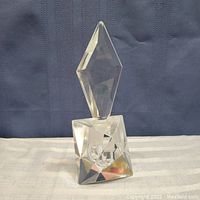 Full view of faceted crystal perfume bottle with tall geometric stopper showing clarity and form.