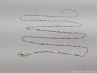 Full view of the 28 inch silver rope chain necklace laid out flat on a white surface showing the full length and clasp.