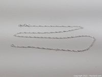 Full length view of the 18 inch sterling silver chain laid flat on a white background.