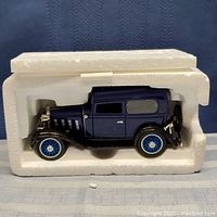 Die cast blue 1932 Standard Coach Car model inside original white styrofoam packaging showing side view.