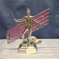 Full view of the mid century chrome musician lamp with stained glass music notes showing the full figure and base with cord and plug.