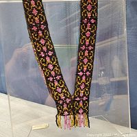 Front view of the full length of the handmade glass beaded necklace showing intricate patterns and fringed ends.