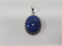 Front view of oval blue stone pendant set in twisted rope sterling silver frame.
