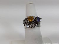 Front angle of the sterling silver ring showing yellow and purple stones and textured bead design on band