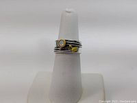Front side view of a sterling silver ring showing yellow and white circular accents and multiple textured layers.